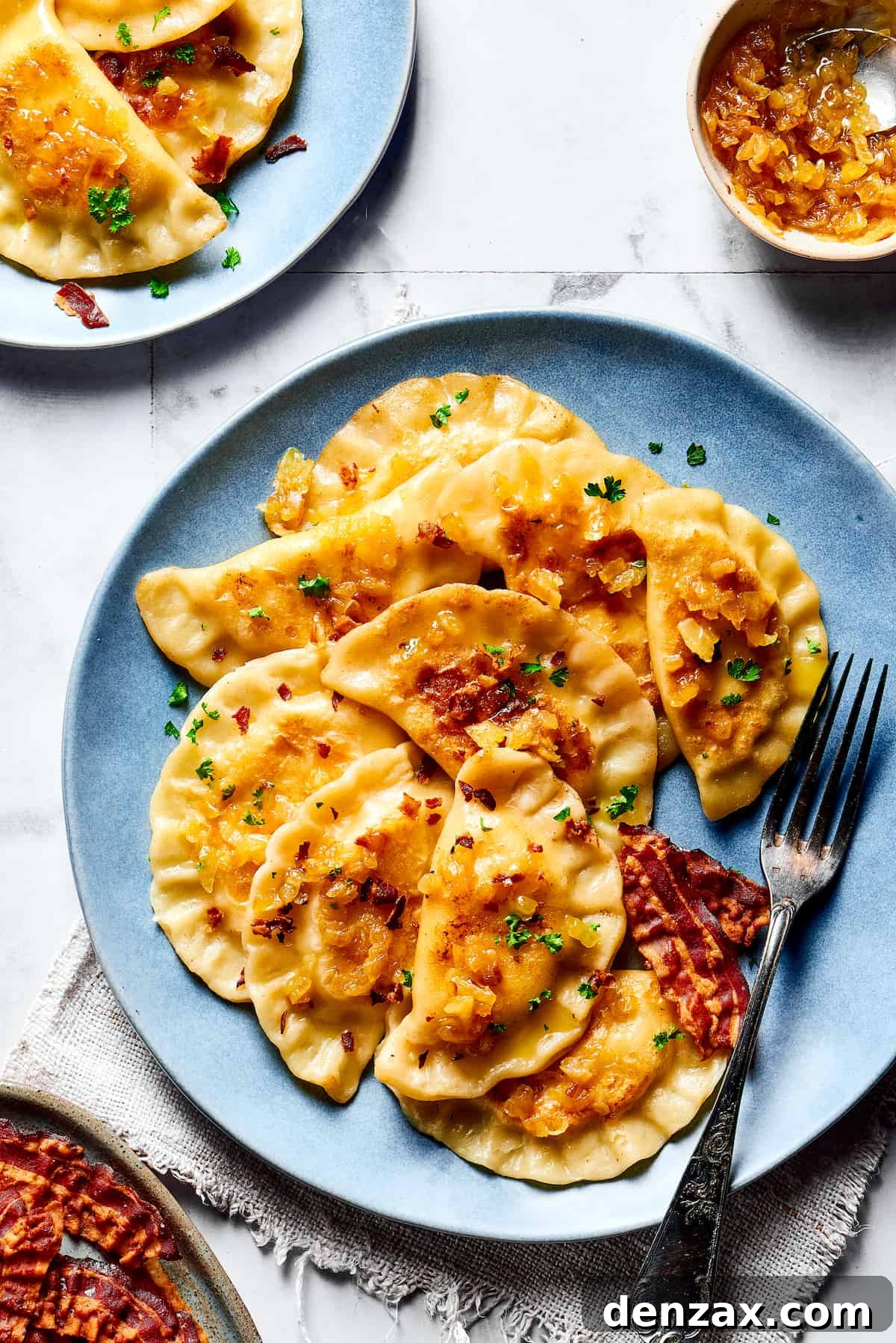 Cooked pierogi beautifully arranged on a plate, generously topped with crispy bacon and caramelized onions.
