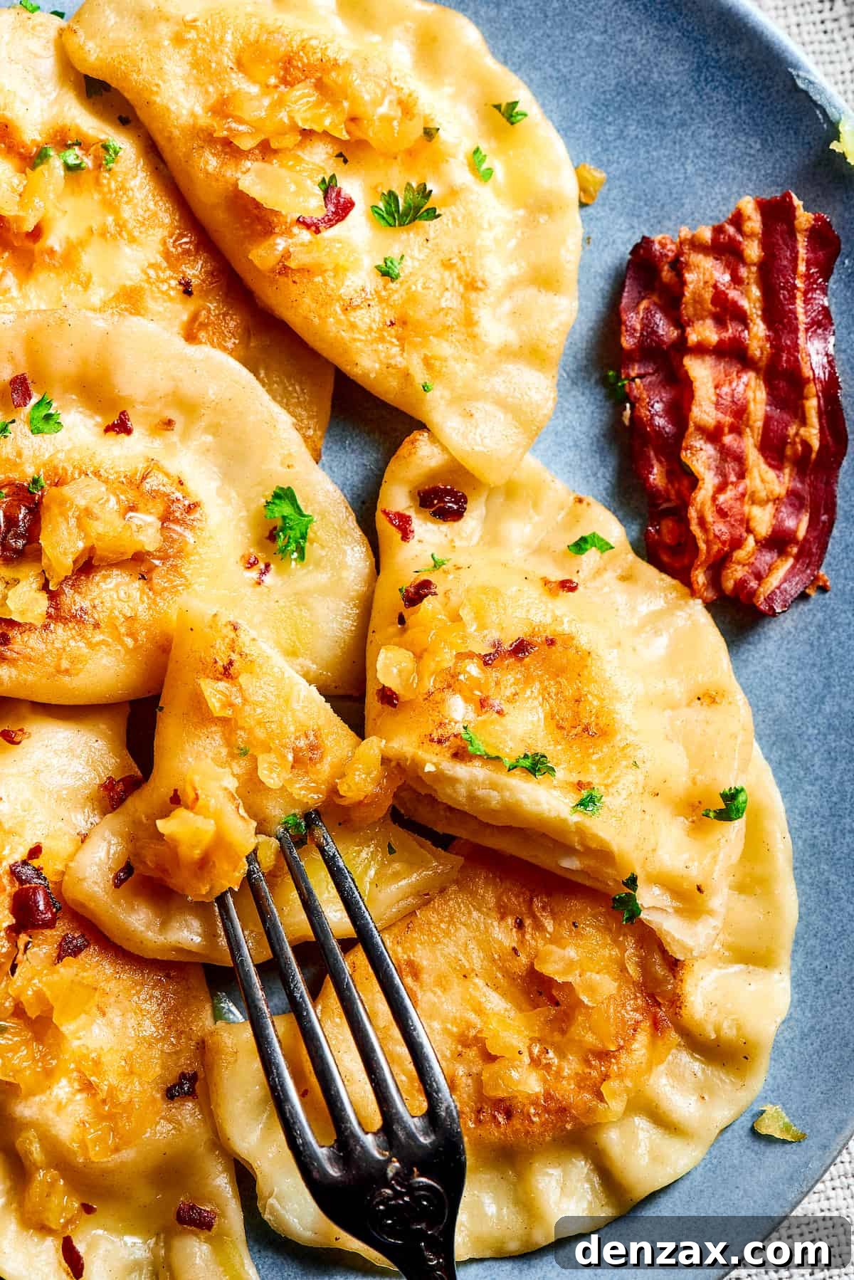 A fork cutting into a homemade potato dumpling, revealing the creamy filling.