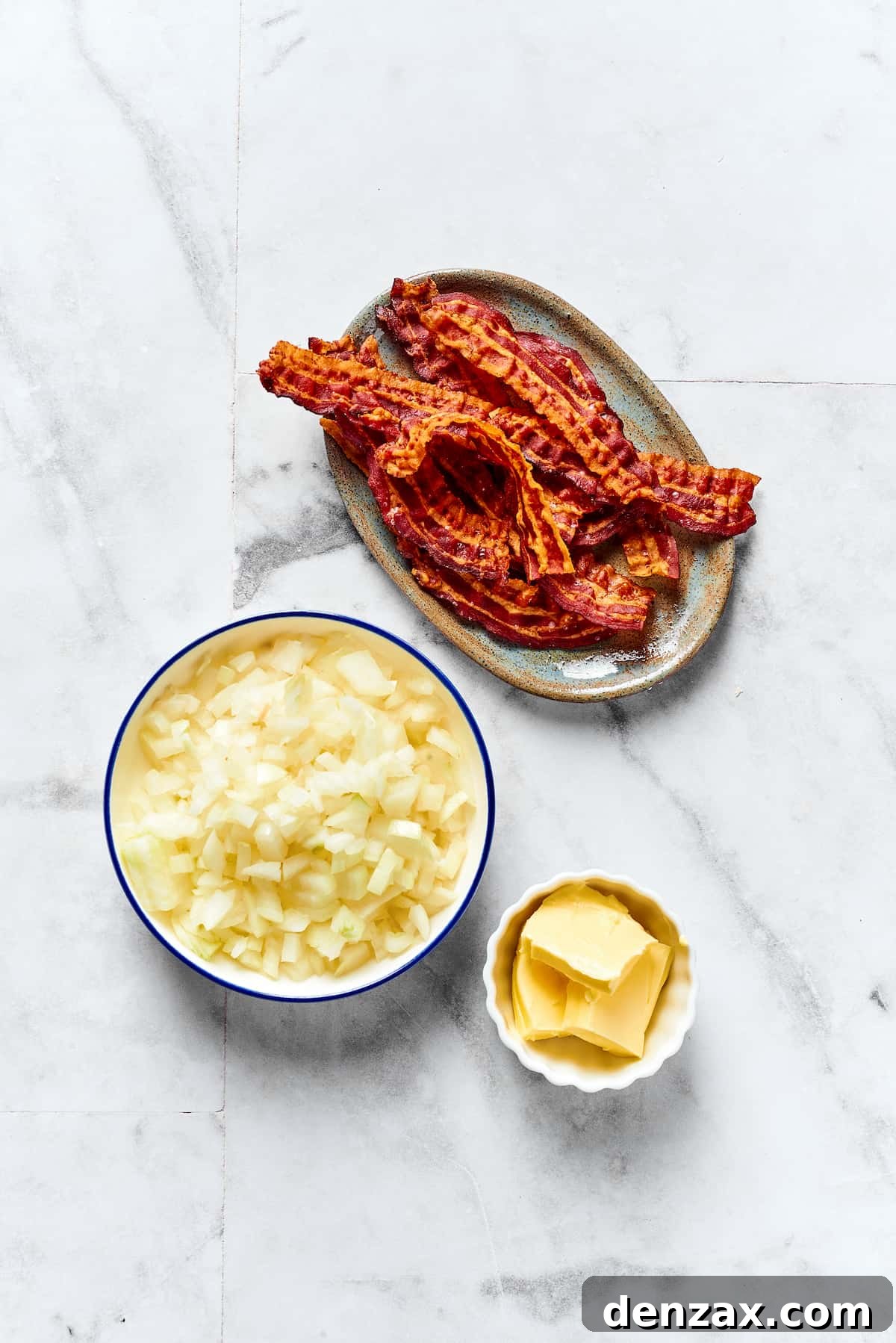 From top: A plate of crisply-cooked bacon, a bowl of chopped onion, and butter sticks.
