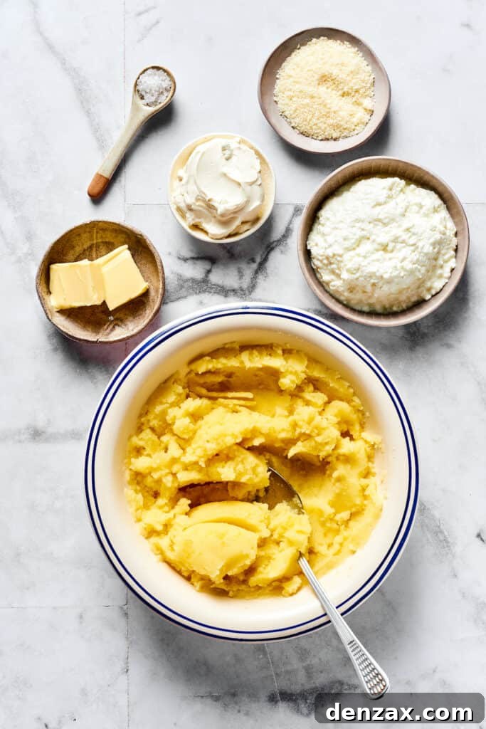 Mashed potatoes in a bowl, surrounded by individual dishes of cottage cheese, sour cream, Parmesan, butter, and salt, ready to be mixed.