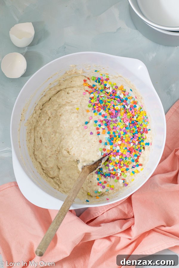 Healthy birthday cake batter being gently mixed in a bowl, showing the consistency before pouring into pans.