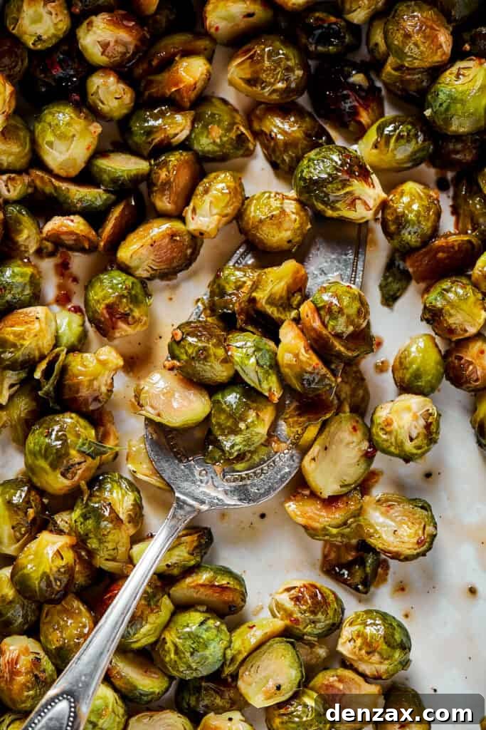 A close-up of roasted Brussels sprouts being gently tossed with the sweet and tangy glaze to ensure even coating.