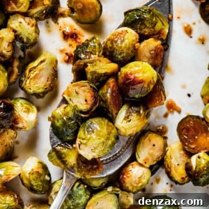 A tray of roasted Brussels sprouts with a silver serving spoon.