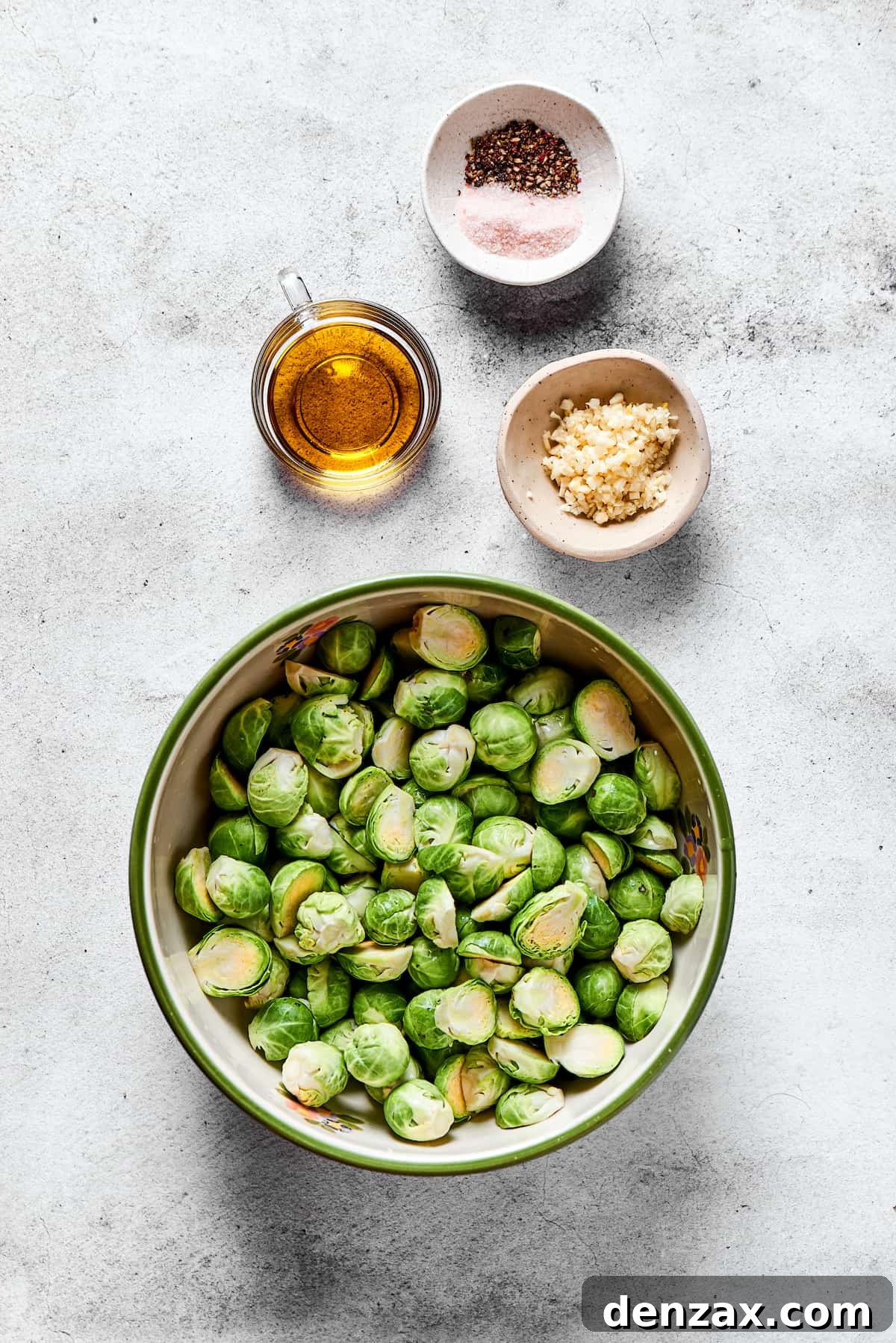Ingredients for roasting: Salt and pepper, olive oil, fresh garlic cloves, and raw halved Brussels sprouts.