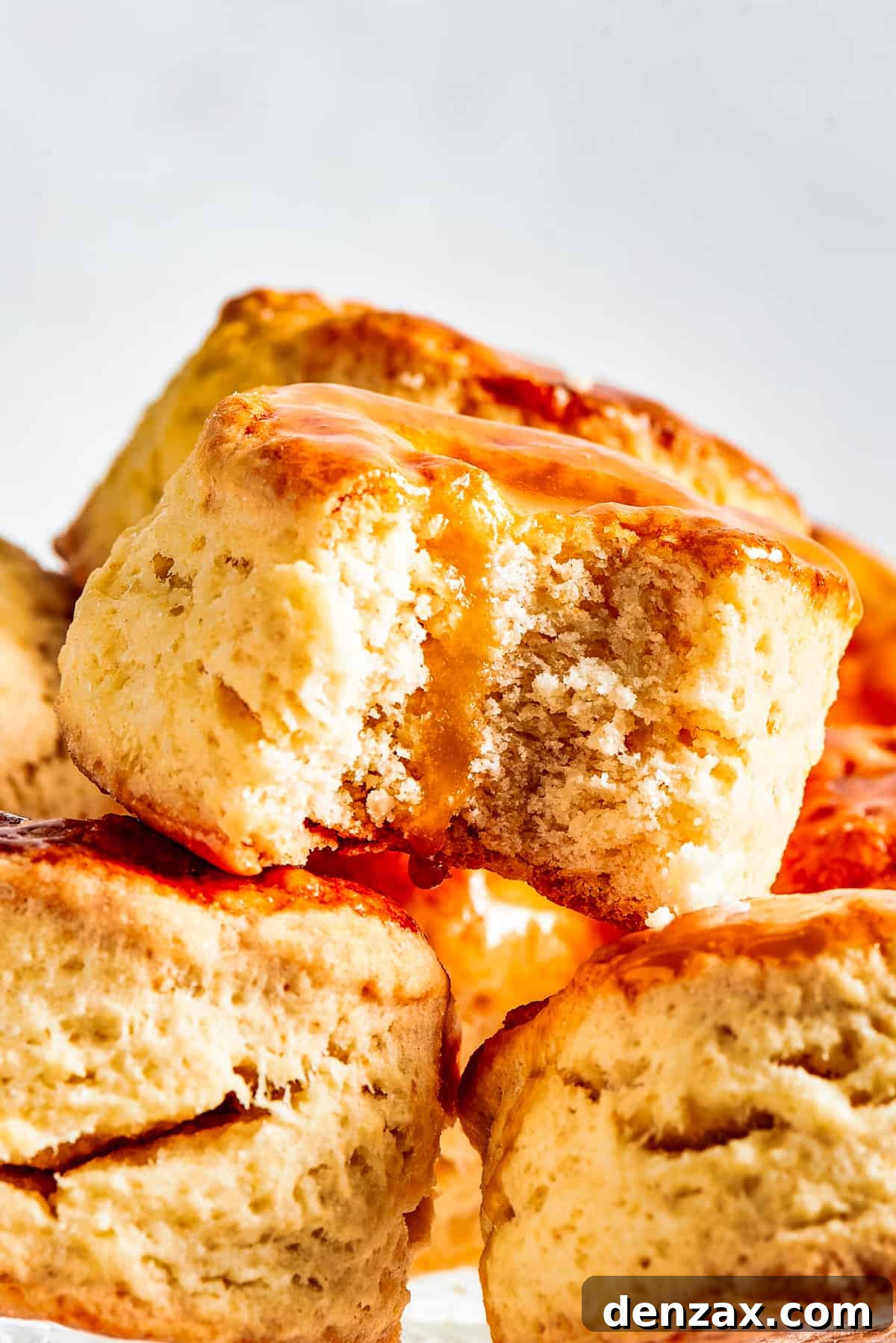 A delightful arrangement of golden-brown biscuits on a cake plate, with one biscuit showing its fluffy interior where a bite has been taken.