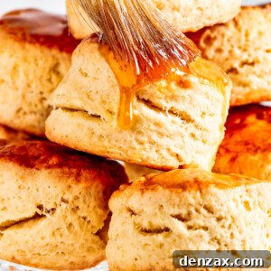 Brushing maple syrup on top of biscuits.