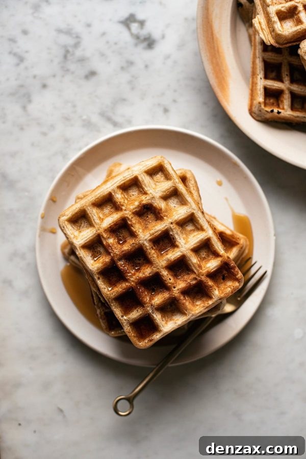 Golden-brown Overnight Sourdough Spelt Waffles, topped with fresh fruit and syrup.