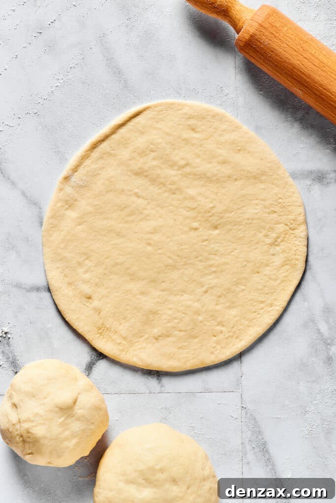 Dough rolled into a thin circle on a floured work surface.