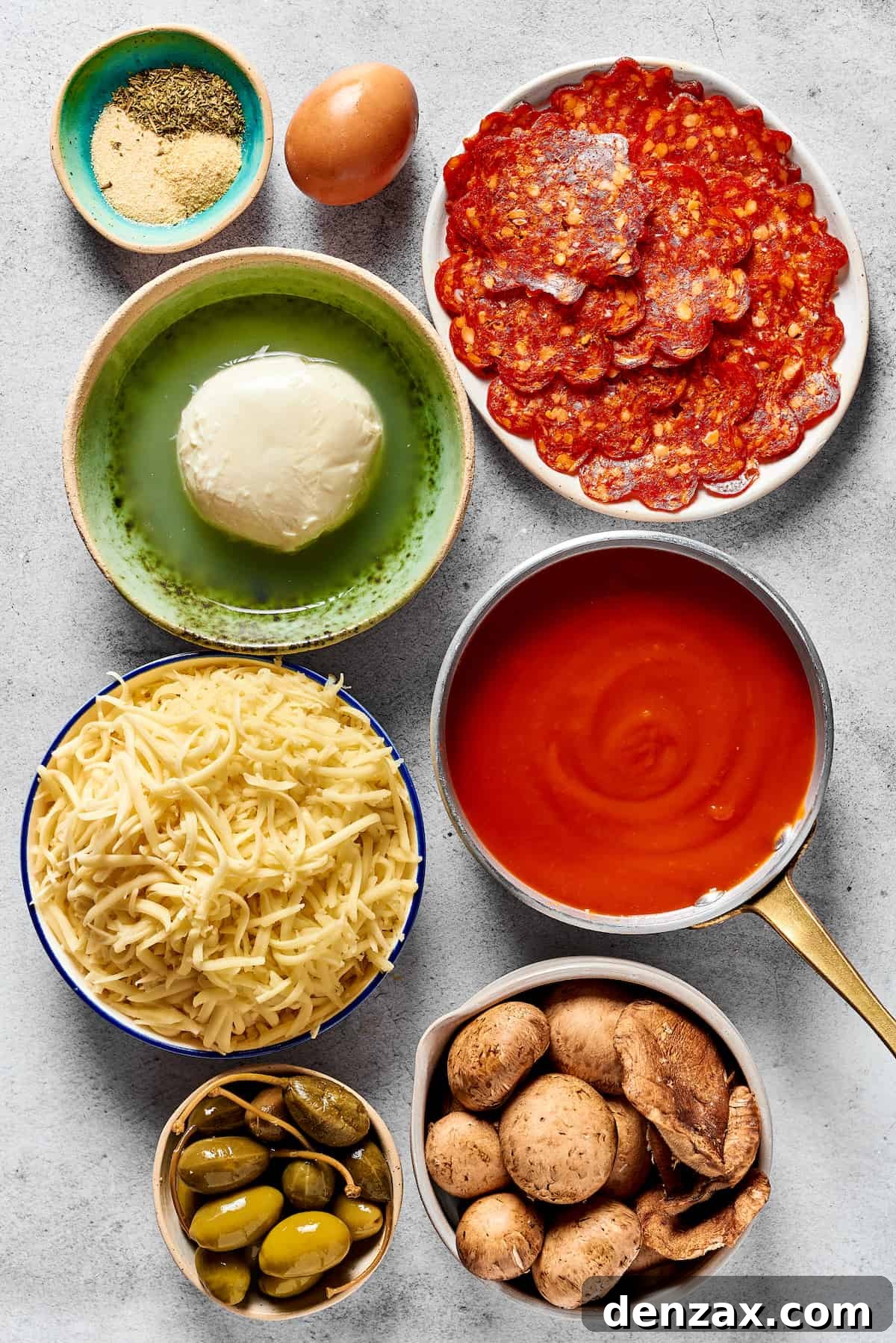 From top: Seasonings, an egg, pepperoni, fresh mozzarella, pizza sauce, shredded cheese, olives and capers, sliced mushrooms.
