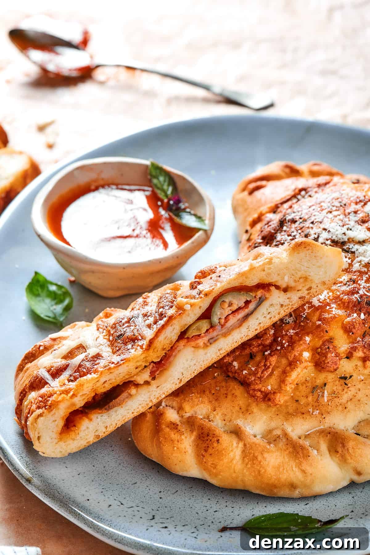 A cut pizza pocket on a blue plate with dipping sauce.