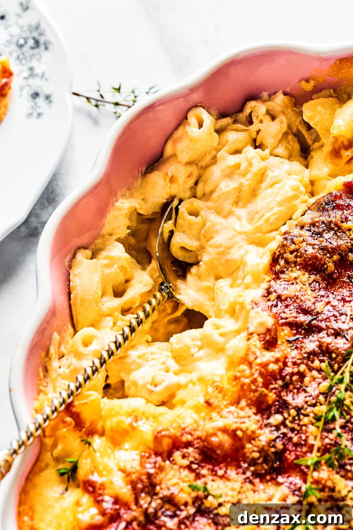 A major family favorite, this ultra-cheesy Baked Macaroni and Cheese is easy to make and perfect for holidays, meatless meals, or anytime! A large serving spoon scooping out a generous portion of freshly baked macaroni and cheese from a casserole dish, highlighting its rich, cheesy texture.