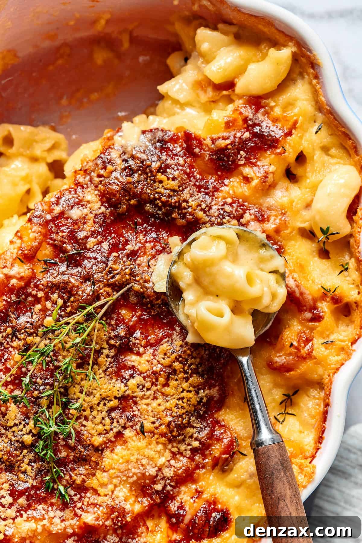 A major family favorite, this ultra-cheesy Baked Macaroni and Cheese is easy to make and perfect for holidays, meatless meals, or anytime! A baking dish filled with baked mac and cheese, with a portion already served, and a serving spoon resting inside, ready for more.