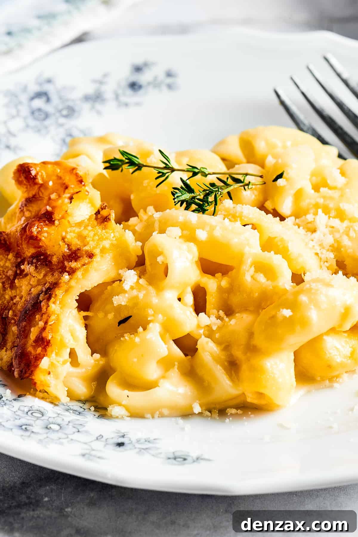 A major family favorite, this ultra-cheesy Baked Macaroni and Cheese is easy to make and perfect for holidays, meatless meals, or anytime! A perfectly portioned serving of baked macaroni and cheese, garnished with fresh herbs, on a floral patterned plate.