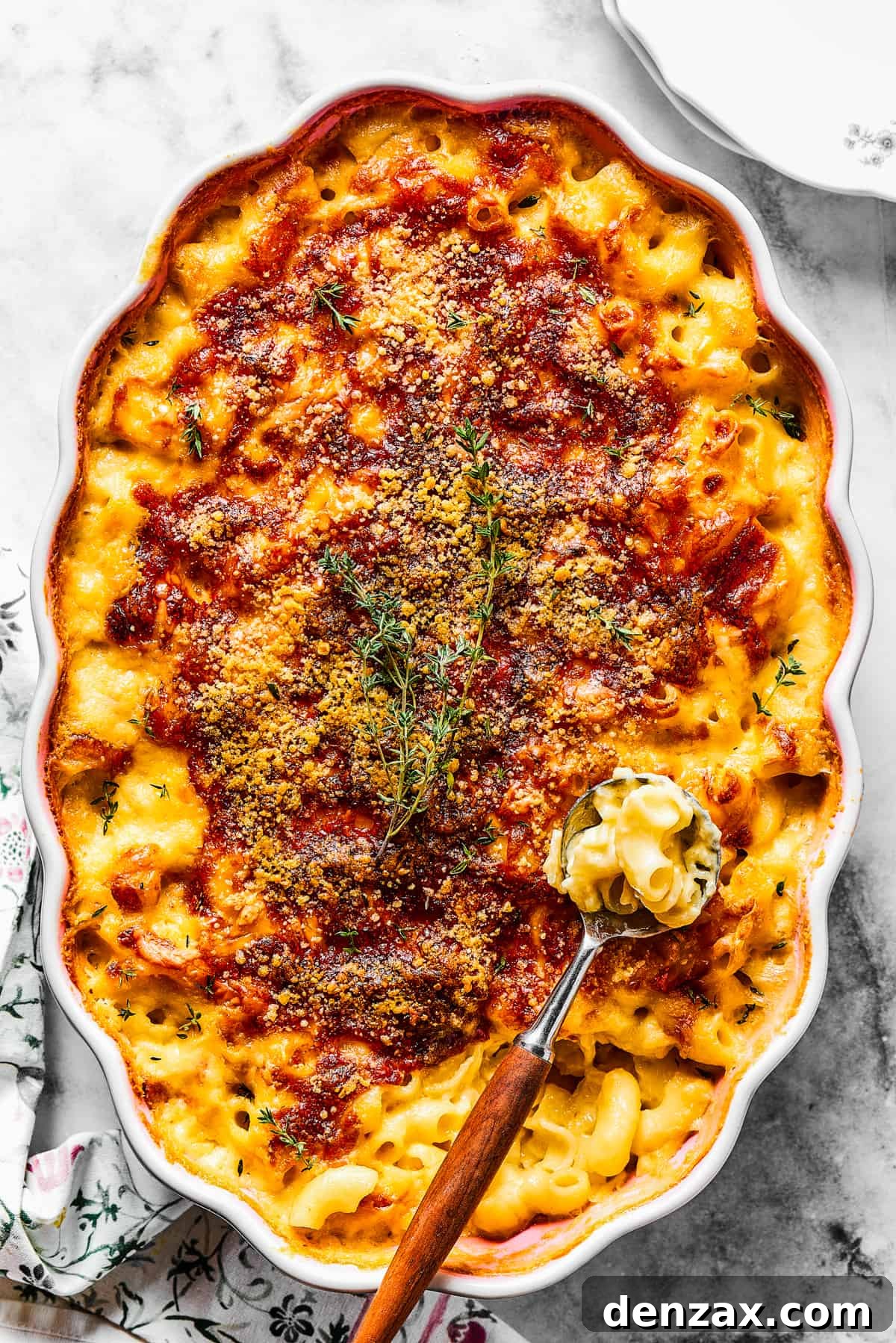 A major family favorite, this ultra-cheesy Baked Macaroni and Cheese is easy to make and perfect for holidays, meatless meals, or anytime! A serving spoon lifting a portion of hot, baked macaroni and cheese from a casserole dish, showing the rich, melted cheese and tender pasta within.