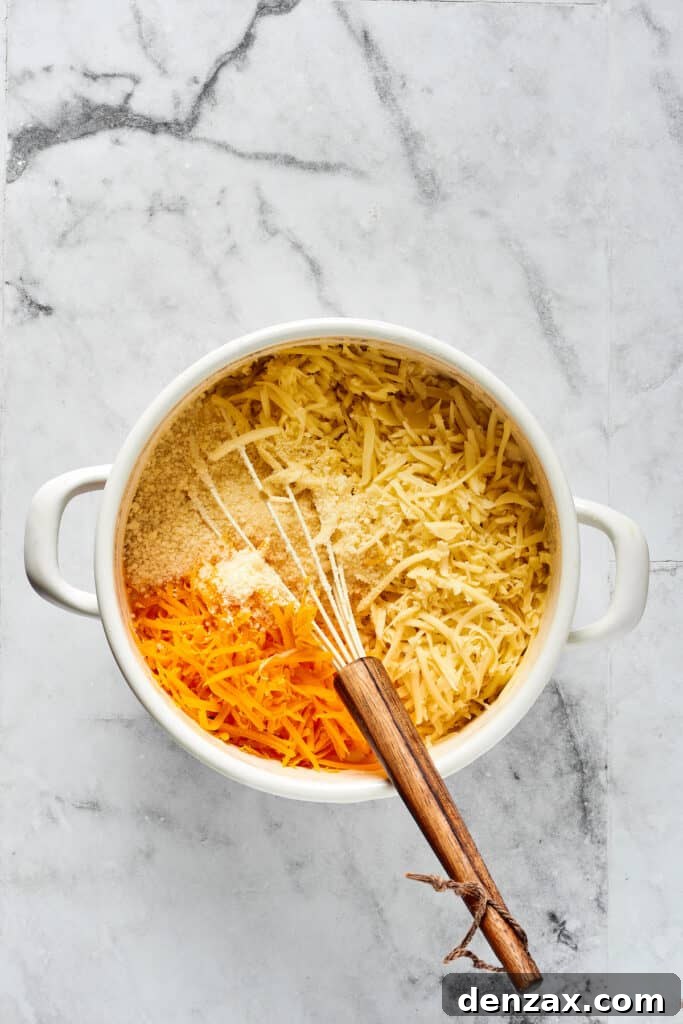 Oven-Baked Cheesy Perfection 4 Hand stirring shredded cheeses and various seasonings into a rich, creamy white sauce in a large pot, demonstrating the creation of the cheese sauce.