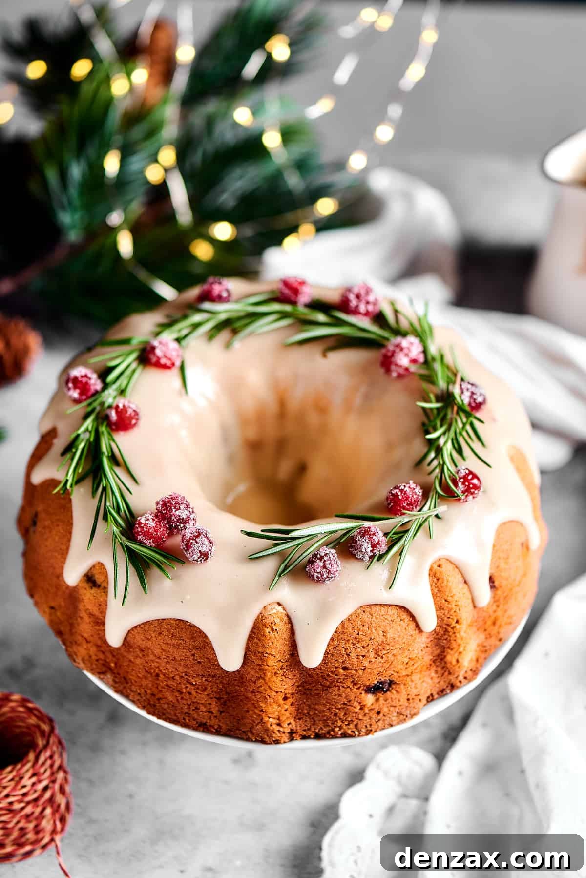 An overhead shot of a beautifully decorated Christmas Cranberry Pound Cake in a Bundt shape, garnished with fresh rosemary sprigs and sugared cranberries.