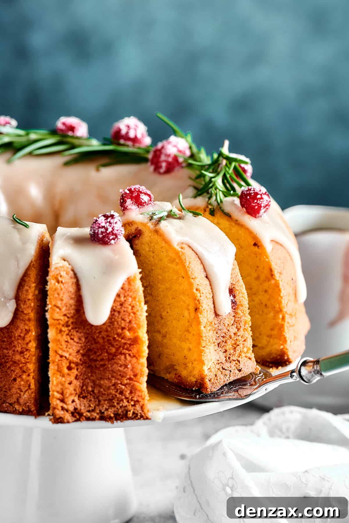 A sliced Christmas Cranberry Pound Cake on a white cake stand, showing its moist interior and cranberry distribution.