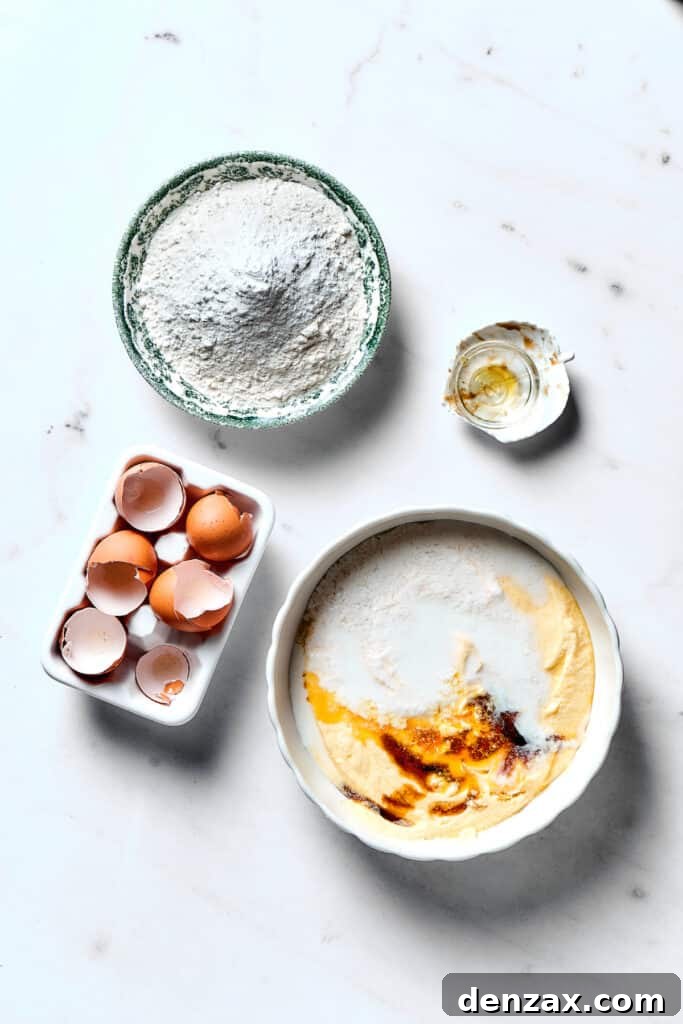 A bowl of wet ingredients mixed in a stand mixer, with dry ingredients waiting in a separate bowl nearby on the counter.