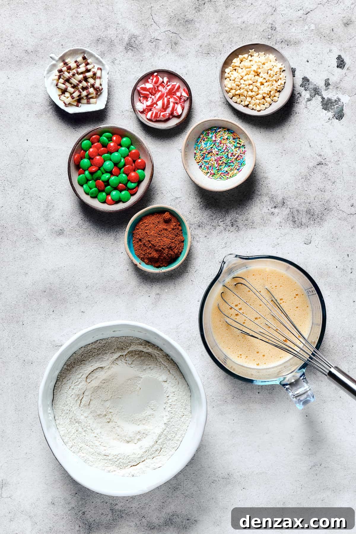 Separate bowls containing blended dry and wet cookie ingredients, with additional decorations and cocoa powder ready to be added, illustrating the preparation stage.
