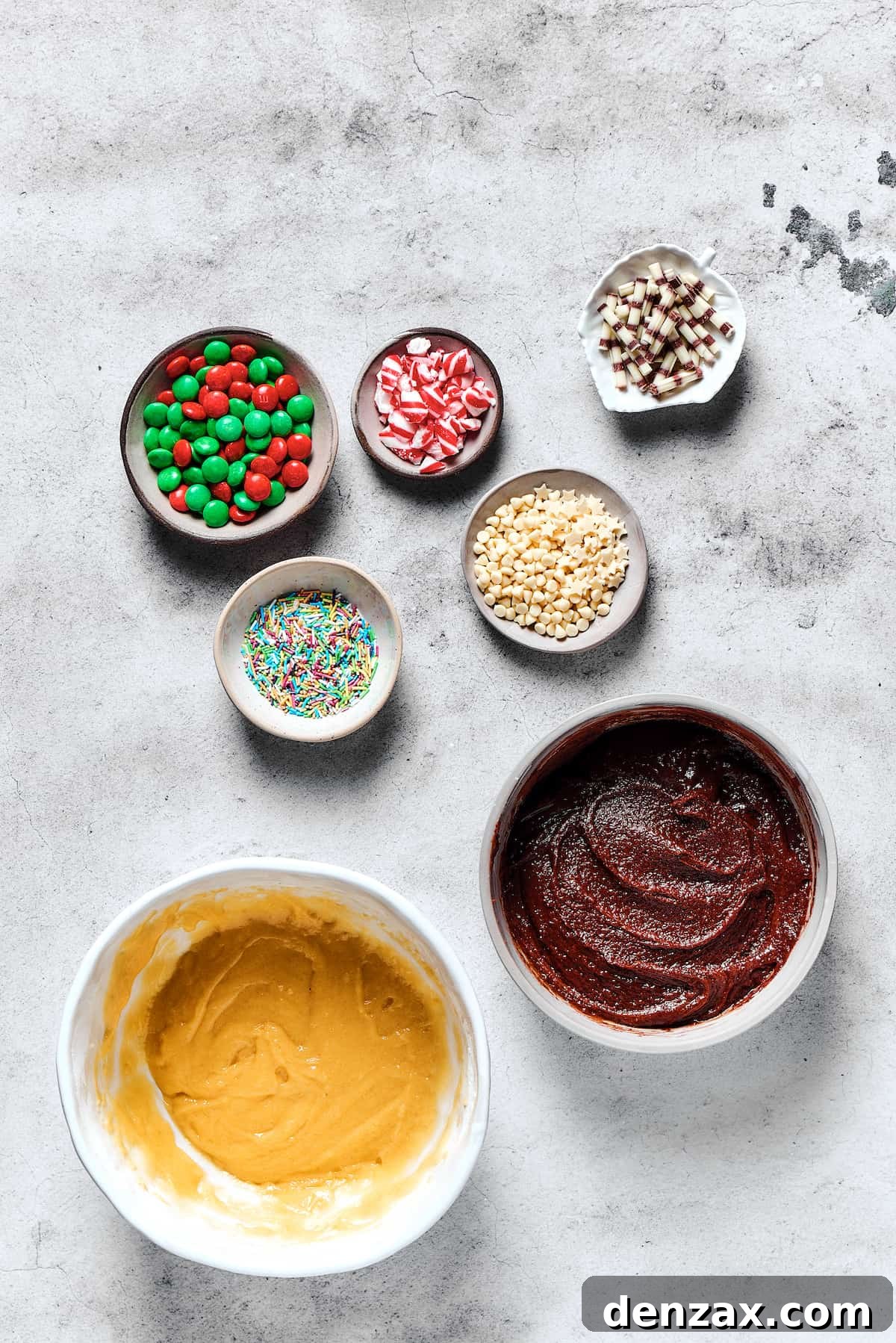 Two separate bowls of cookie dough: one vanilla, one chocolate, positioned beside small dishes of festive M&M's and sprinkles, ready for shaping and decoration.