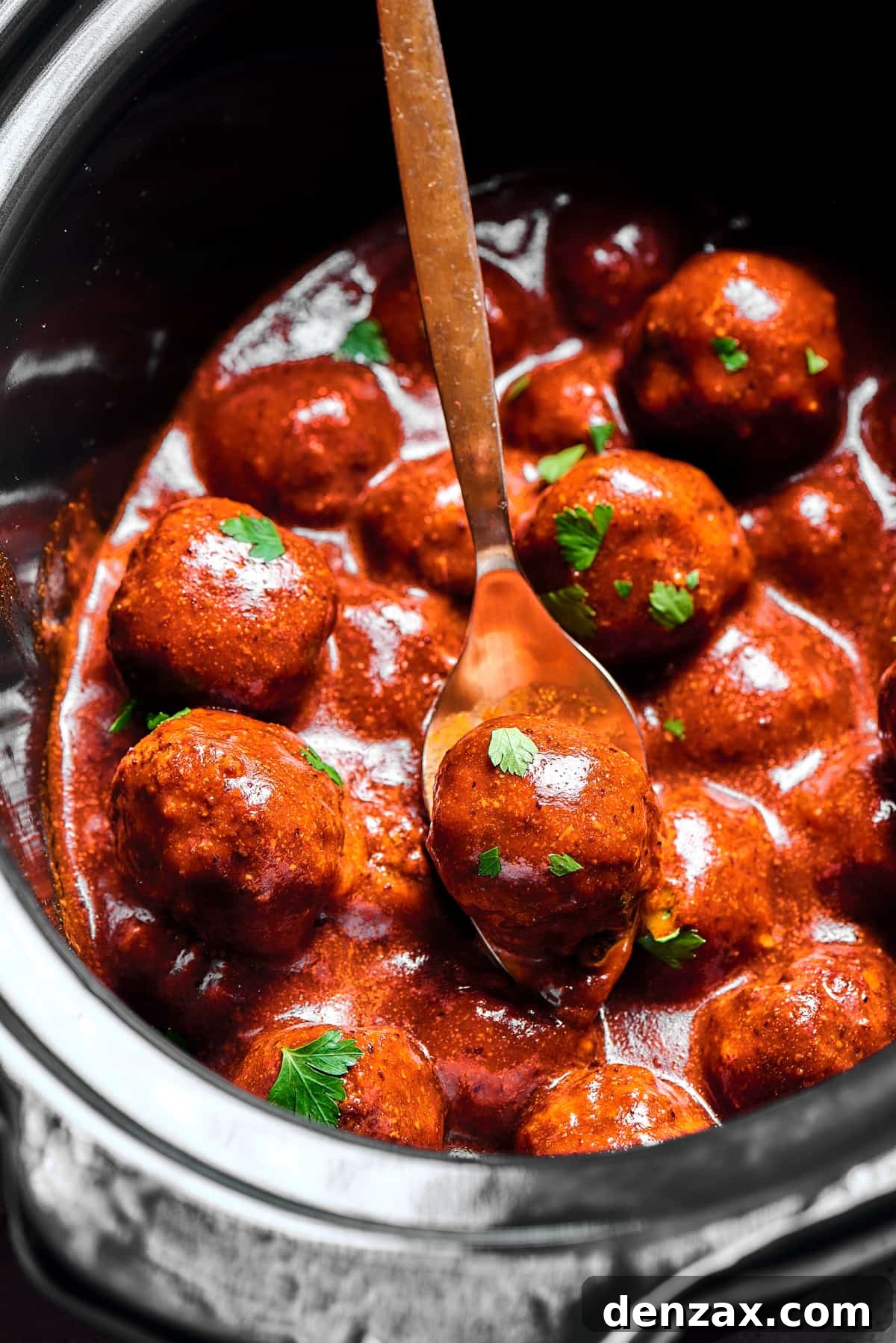 A slow cooker viewed from the top, filled with grape jelly meatballs.
