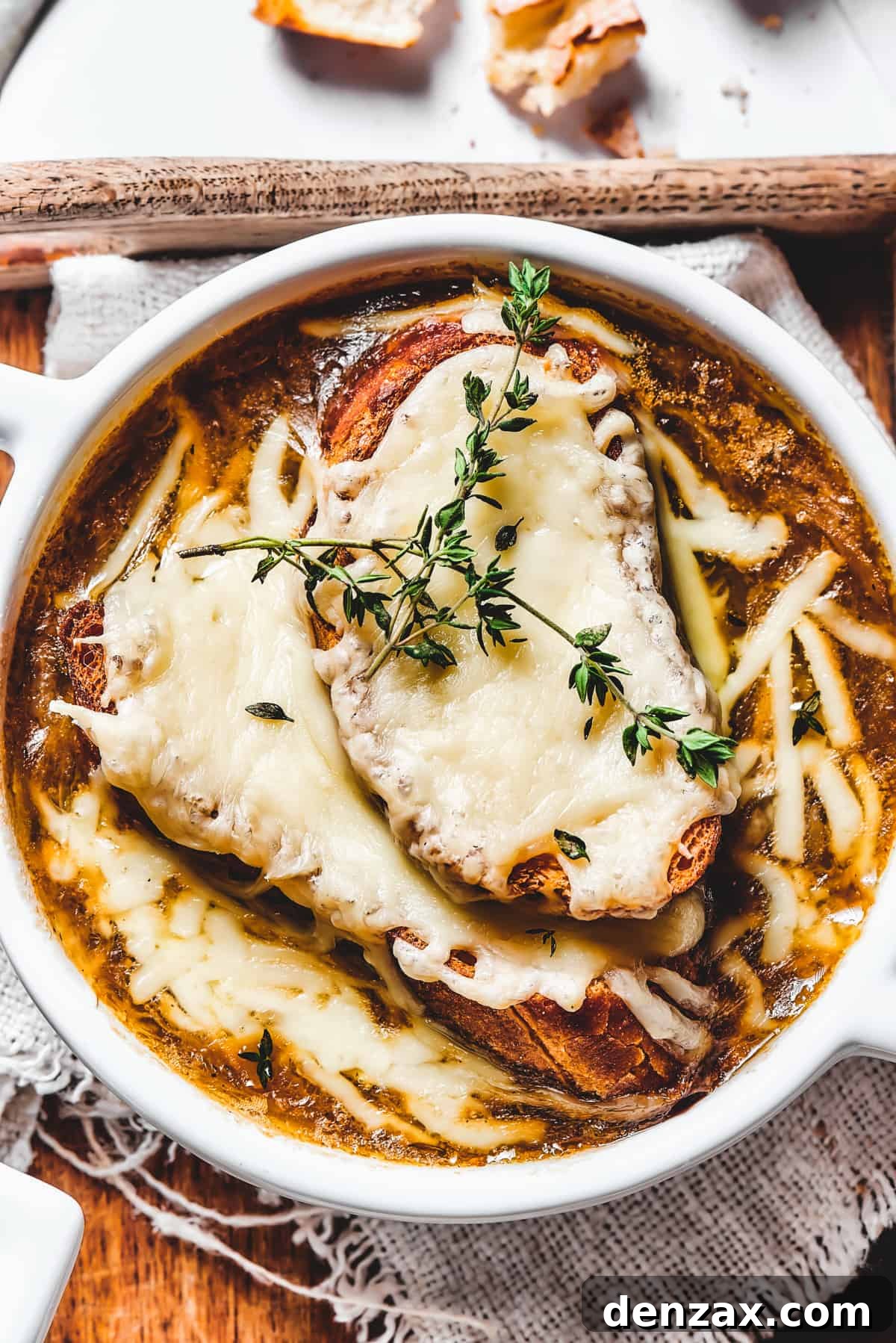 Overhead shot of French Onion Soup in a classic crock with melted cheese and a thyme garnish.