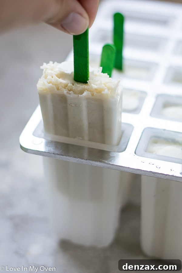 Freshly demolded coconut lime popsicle, ready to be enjoyed on a hot day.
