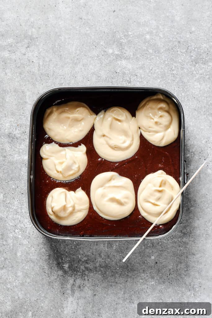 Marbled Chocolate Cheesecake Brownies 10 Dollops of white cream cheese generously spread over the dark brownie batter, ready for swirling.