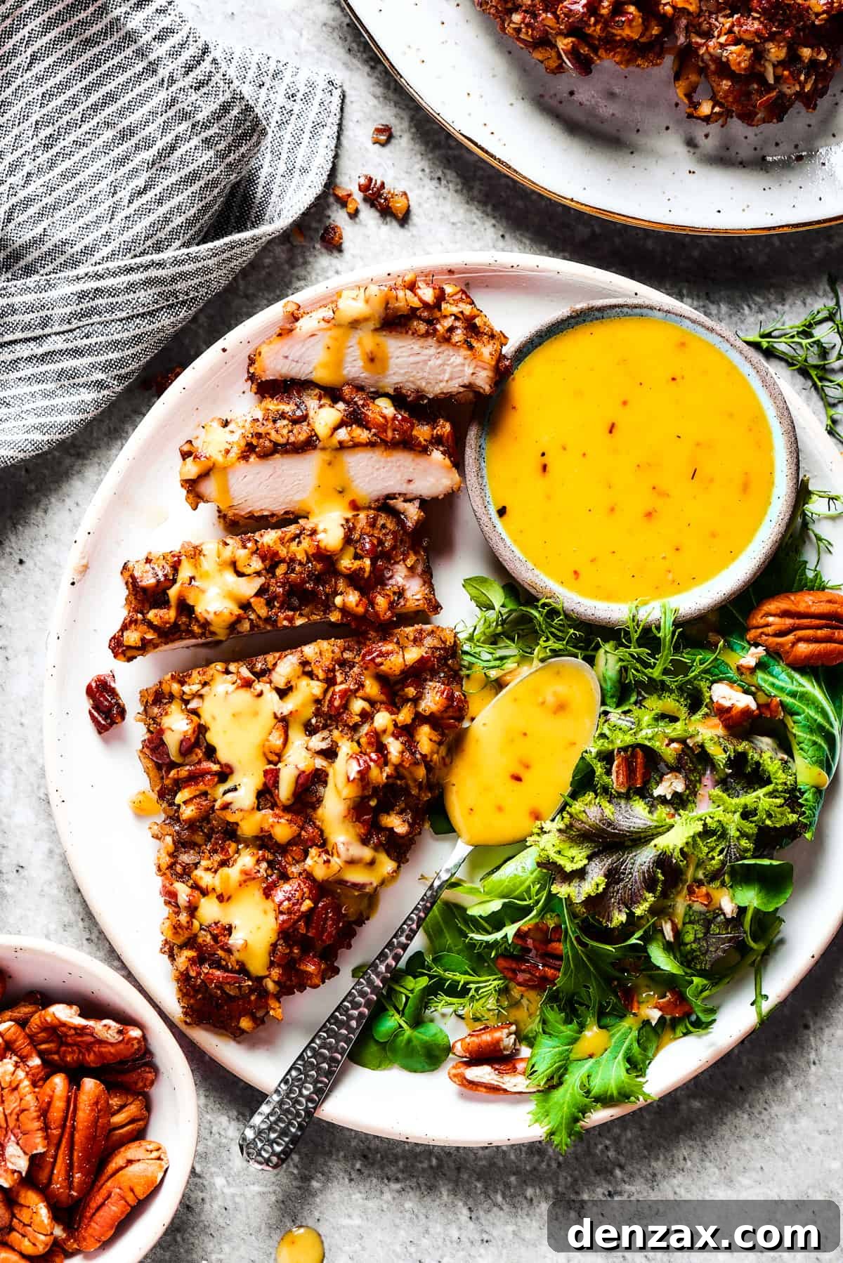 A perfectly cooked breast of pecan crusted chicken, expertly sliced and served on a dinner plate, showcasing its golden crust and juicy interior.