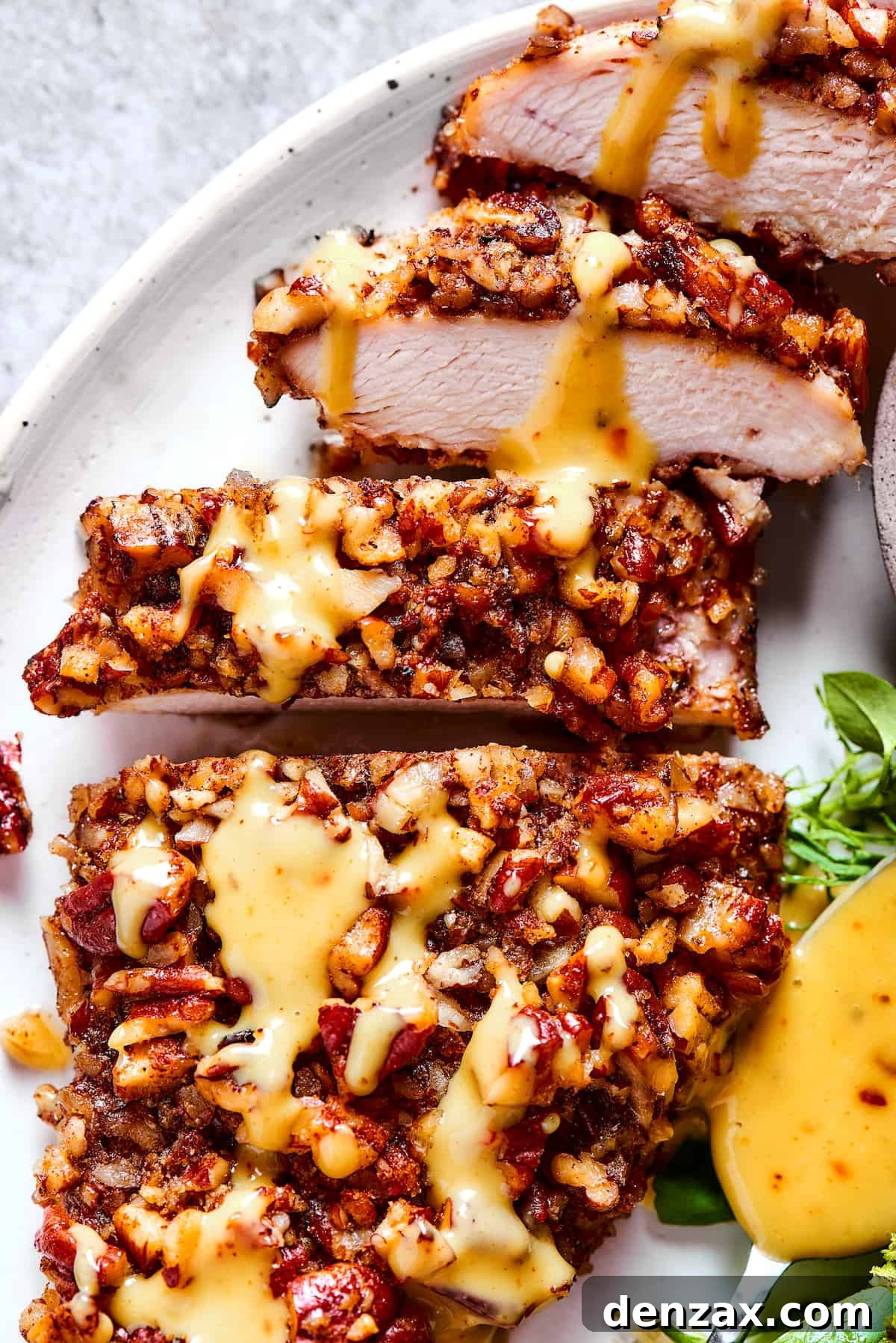 Close-up shot of perfectly golden-brown, sliced pecan crusted chicken, revealing its inviting crunchy texture and juicy interior.