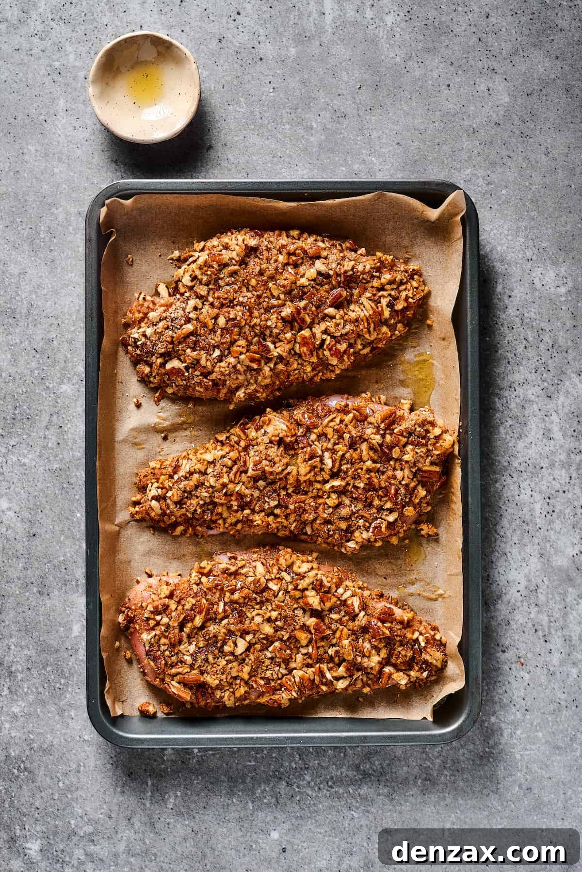 Pecan-coated chicken breasts meticulously arranged on a baking sheet, showcasing their ready-to-bake or freshly baked golden appearance.