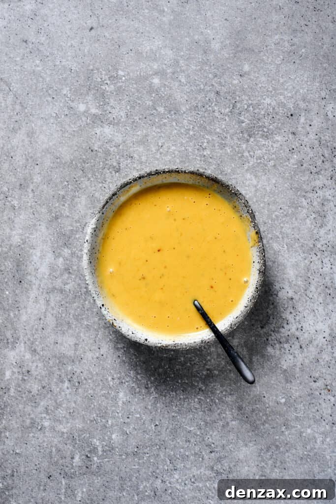 A charming small earthenware bowl brimming with smooth, golden honey mustard sauce, perfect for dipping or drizzling.