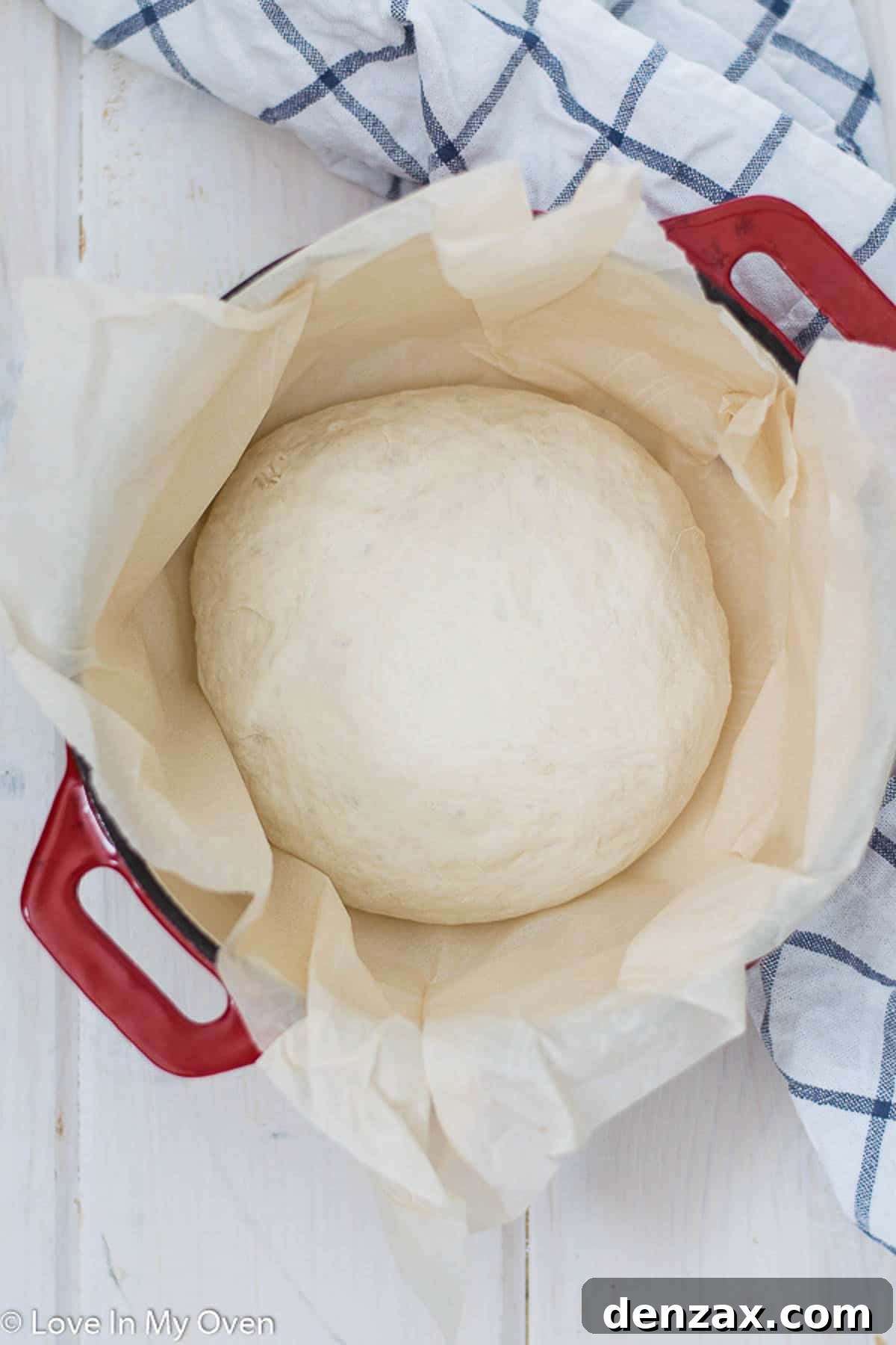 Scored dough carefully placed inside a hot Dutch oven, ready to bake.