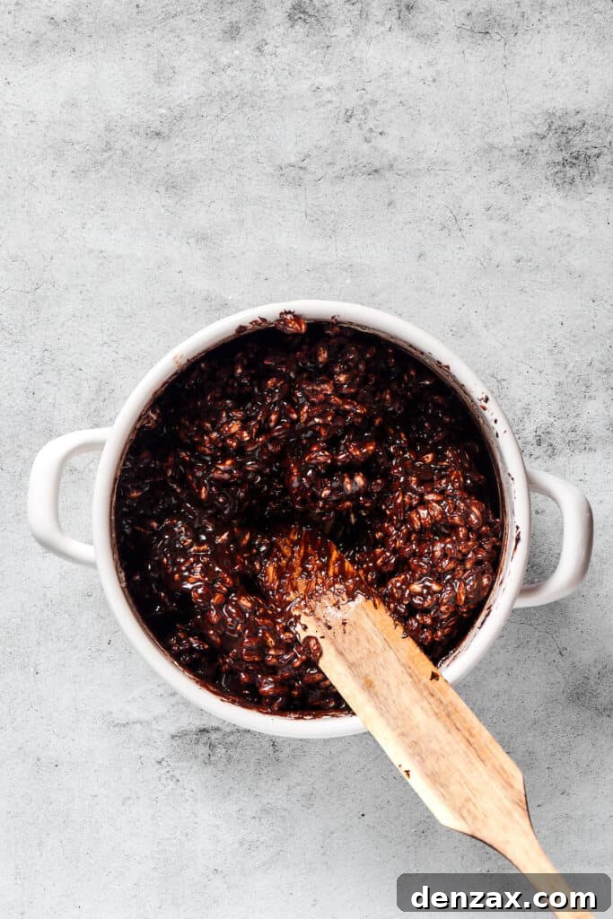 The vibrant chocolate rice cereal mixture glistening in a large pot, perfectly coated and ready to be transferred.