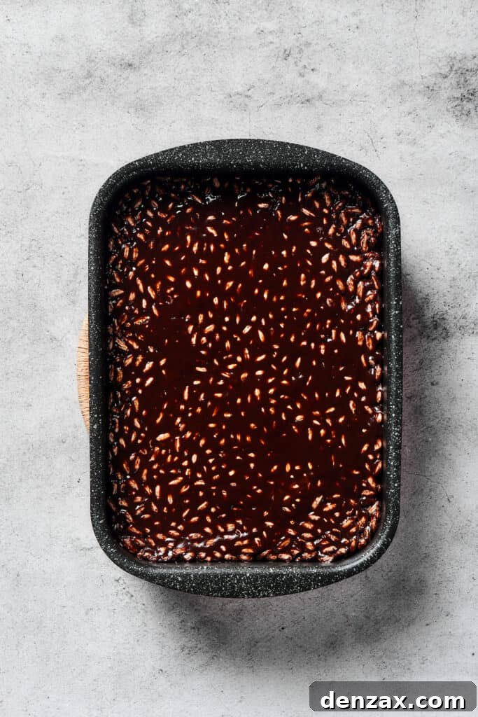 A freshly pressed pan of chocolate rice cereal treats, cooling and setting into a delicious no-bake dessert.