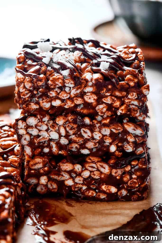 Artfully stacked squares of chocolate rice krispie treats, each generously adorned with a tempting chocolate topping, ready to be enjoyed.