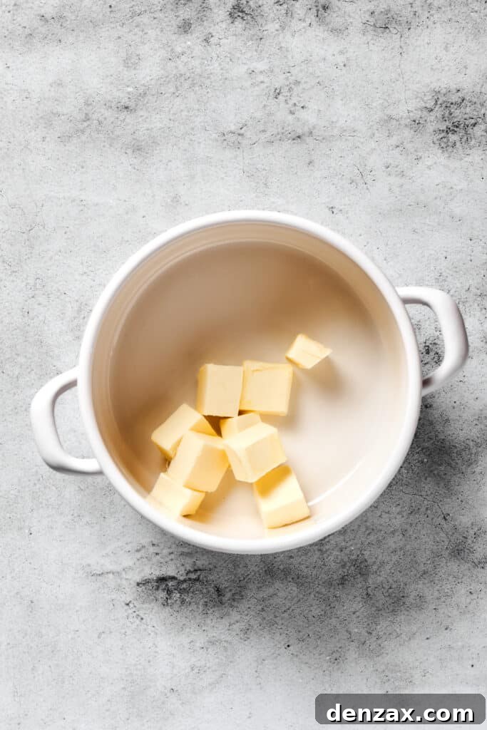 Golden butter melting gently in a saucepan over low heat, preparing for the marshmallow mixture.