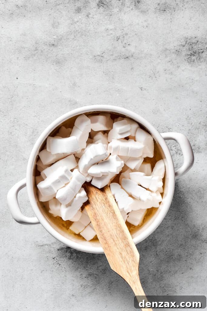 Fluffy marshmallows being stirred into luscious melted butter in a saucepan, beginning to transform into a gooey base.