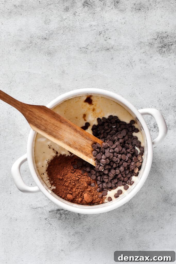 Dark chocolate chips and rich cocoa powder being stirred into the warm, gooey marshmallow and butter mixture, creating a deeply chocolatey base.