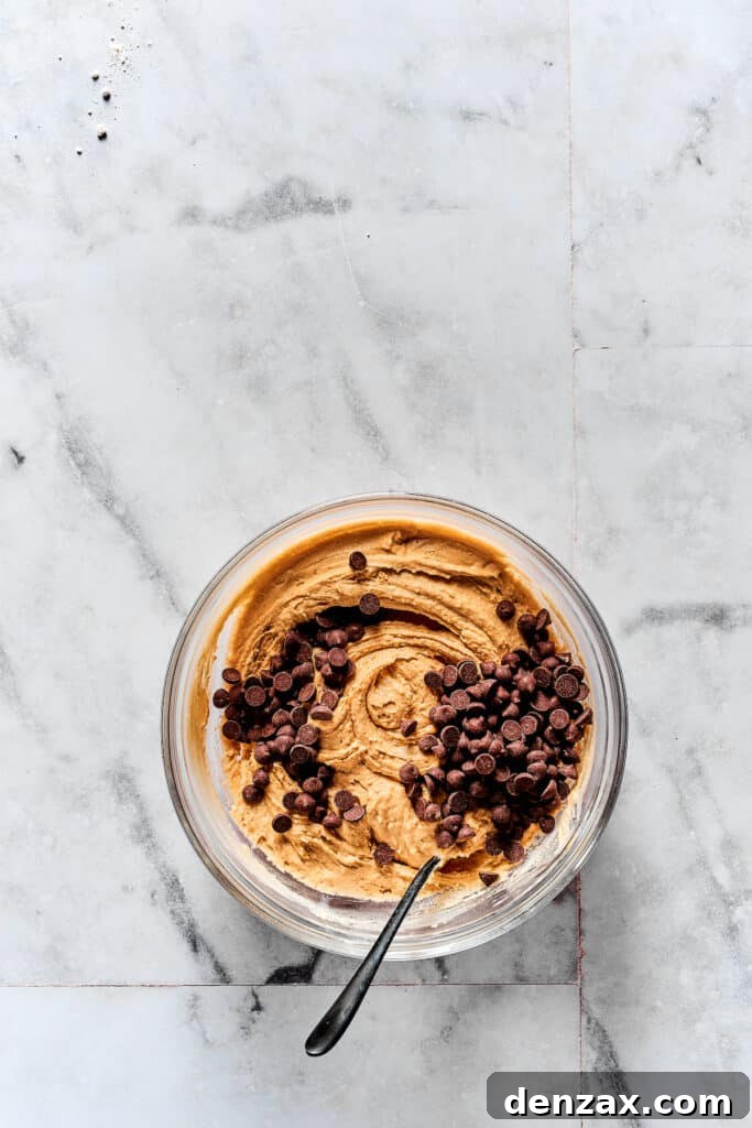 Adding mini chocolate chips to the prepared edible cookie dough mixture.