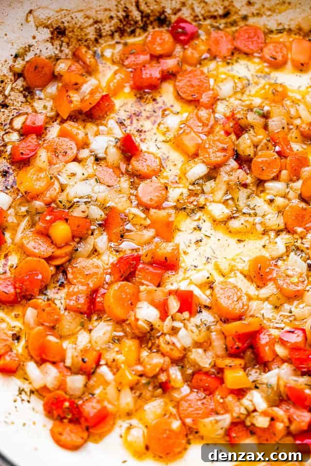 frying carrots and onions in a white skillet