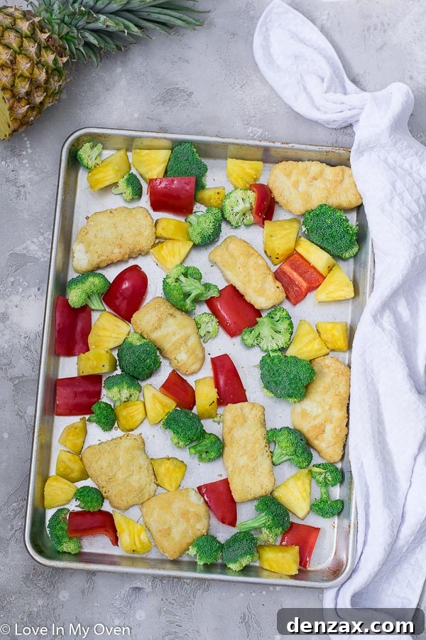 sheet pan with fish, pineapple, and vegetables in the oven