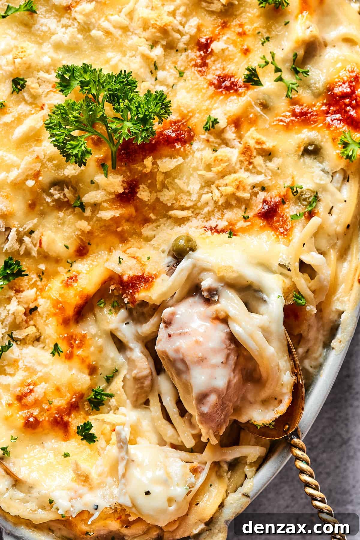 Scooping a generous portion of chicken tetrazzini out of the serving dish, highlighting its creamy consistency and ample portions.