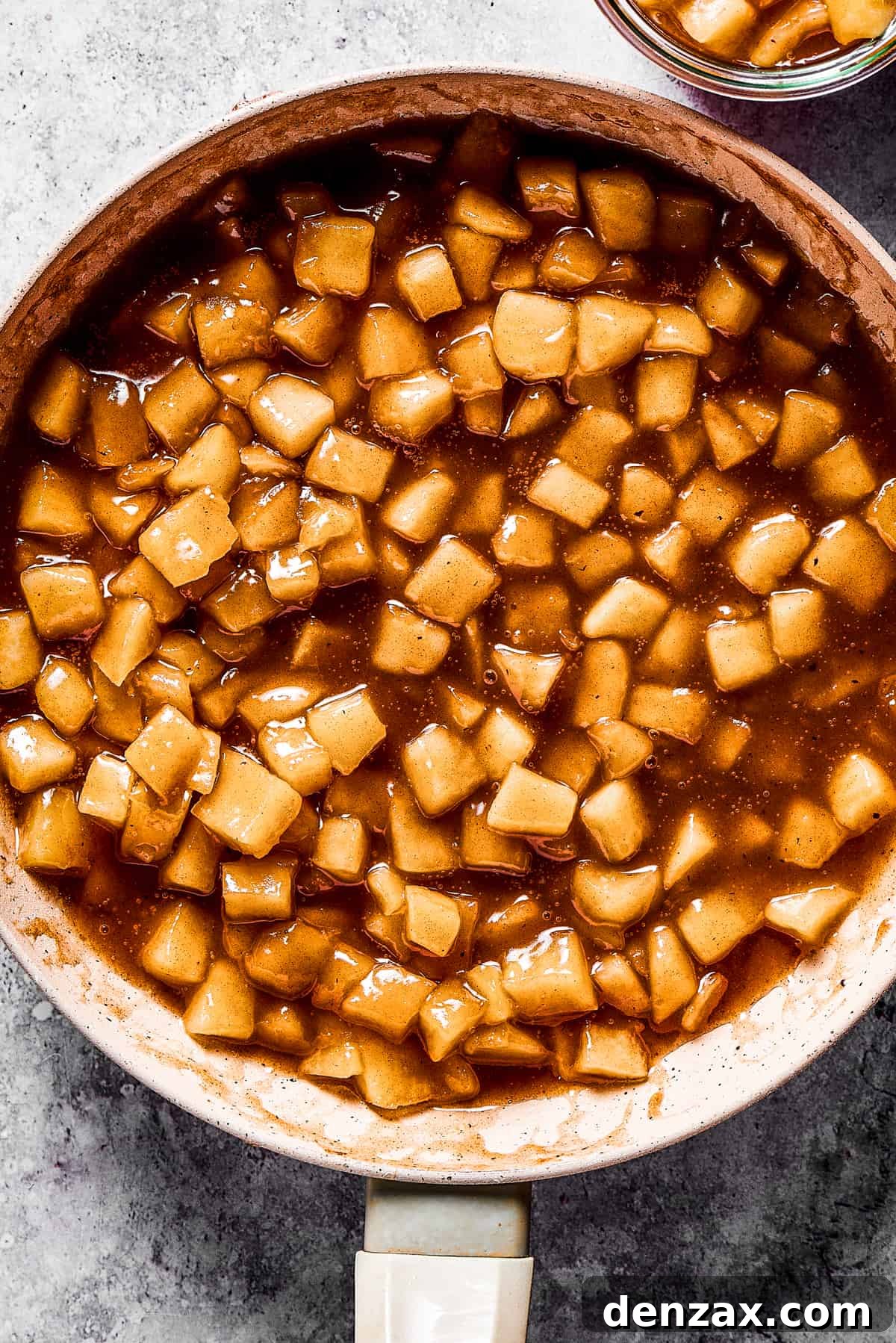 Homemade apple pie filling being made in a skillet, showcasing its rich color and tender texture.