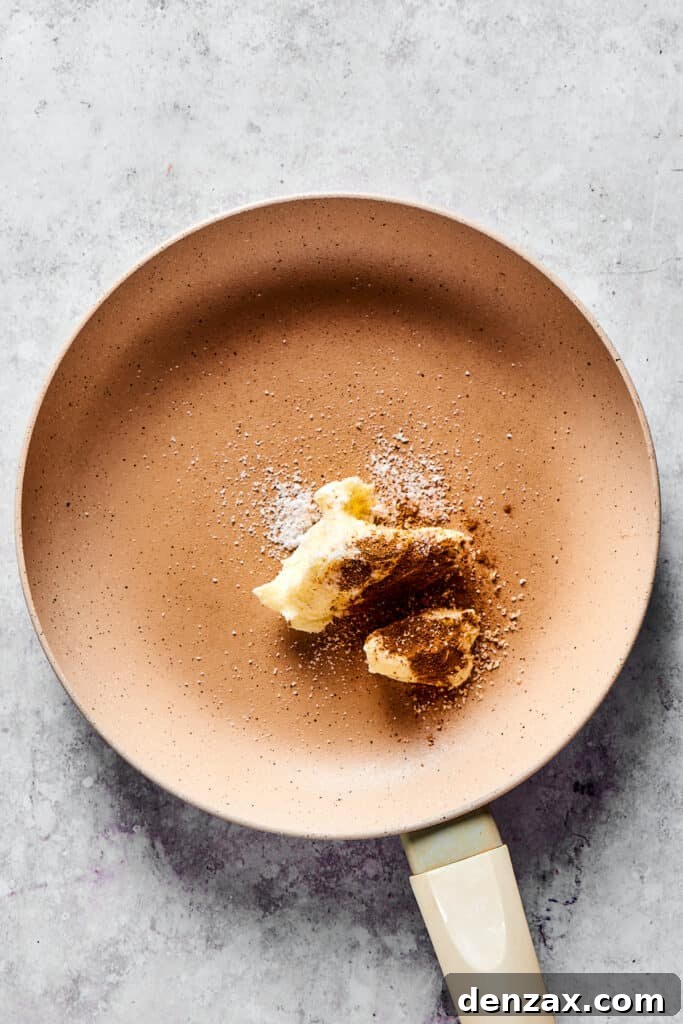 Melted butter shimmering in a skillet, gently infused with aromatic cinnamon and nutmeg, forming the flavorful base.