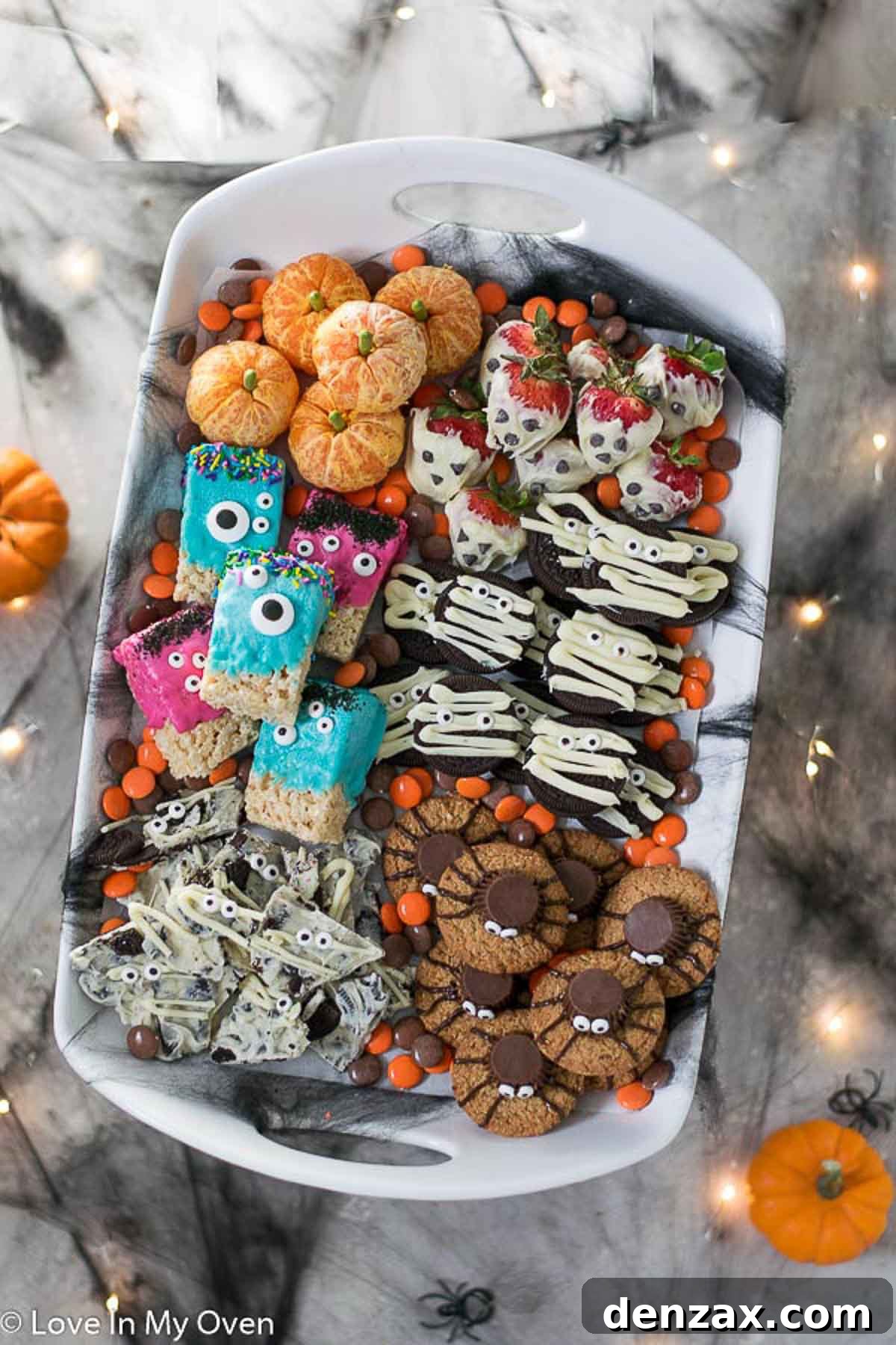 Spooky Sweet Creations for Kids 2 A platter featuring various easy Halloween treats for kids, including spider cookies, mummy bark, orange pumpkins, and monster rice krispie squares.
