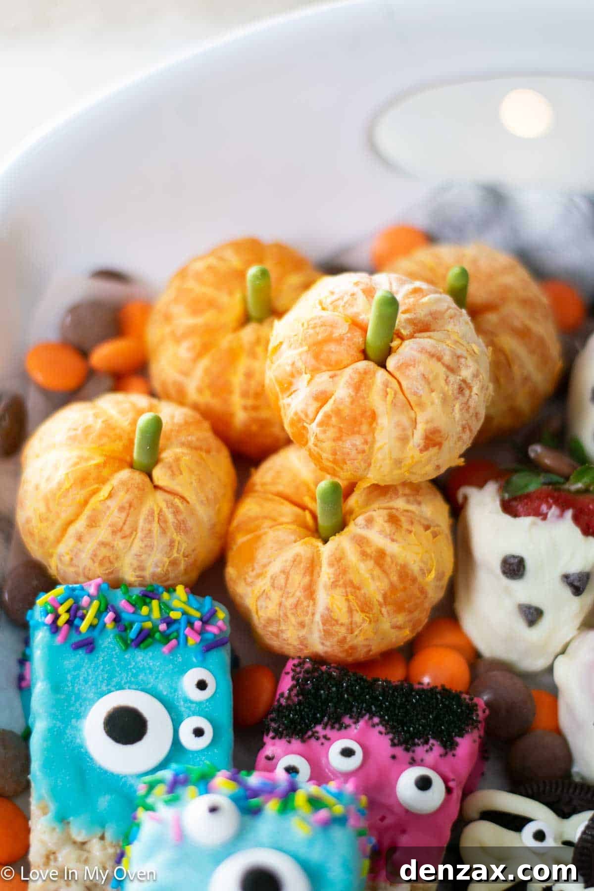 Spooky Sweet Creations for Kids 8 Easy orange pumpkins, made from peeled mandarin oranges with green candy stems, arranged on a spooky platter.