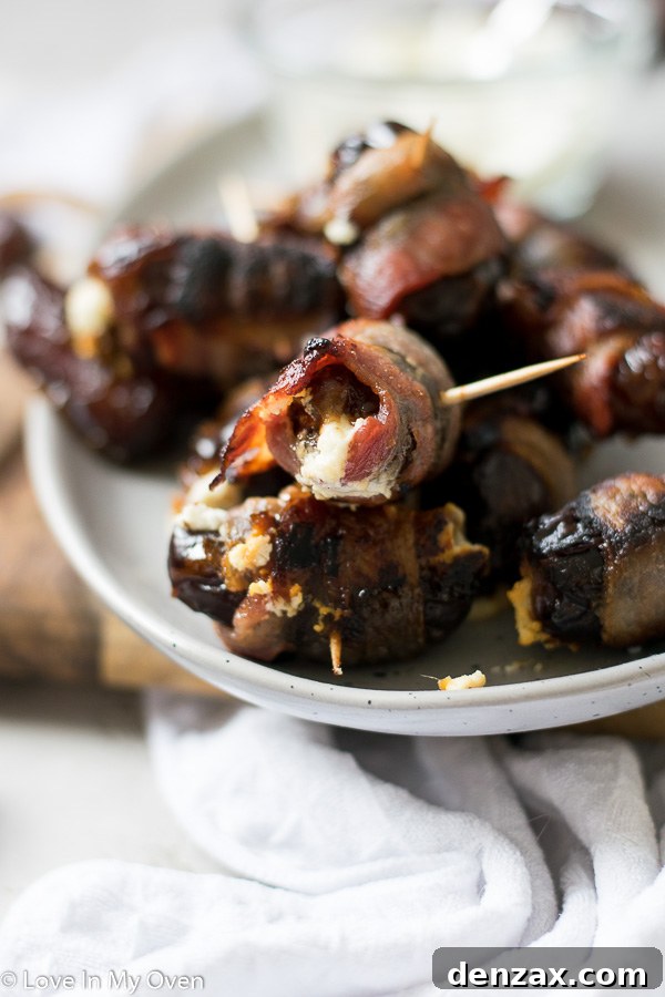 Two bacon-wrapped stuffed dates on a dark surface, highlighting their appealing texture and savory-sweet combination.