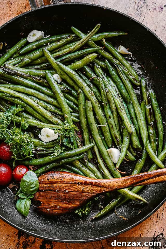 Fresh green beans cooking in a black skillet with butter and garlic
