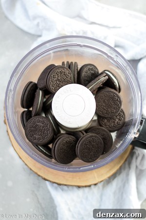 Oreo cookies being crushed in a food processor, capturing the initial step